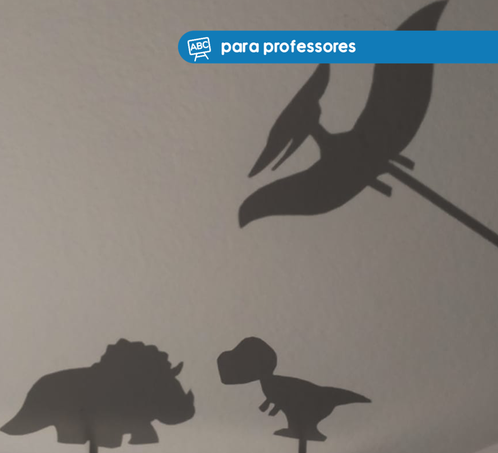 Imagem composta de três sombras na parede, cada uma possui o formato de um dinossauro. Na parte superior, à direita, está a tag "para professores" em azul, com letras em branco. 