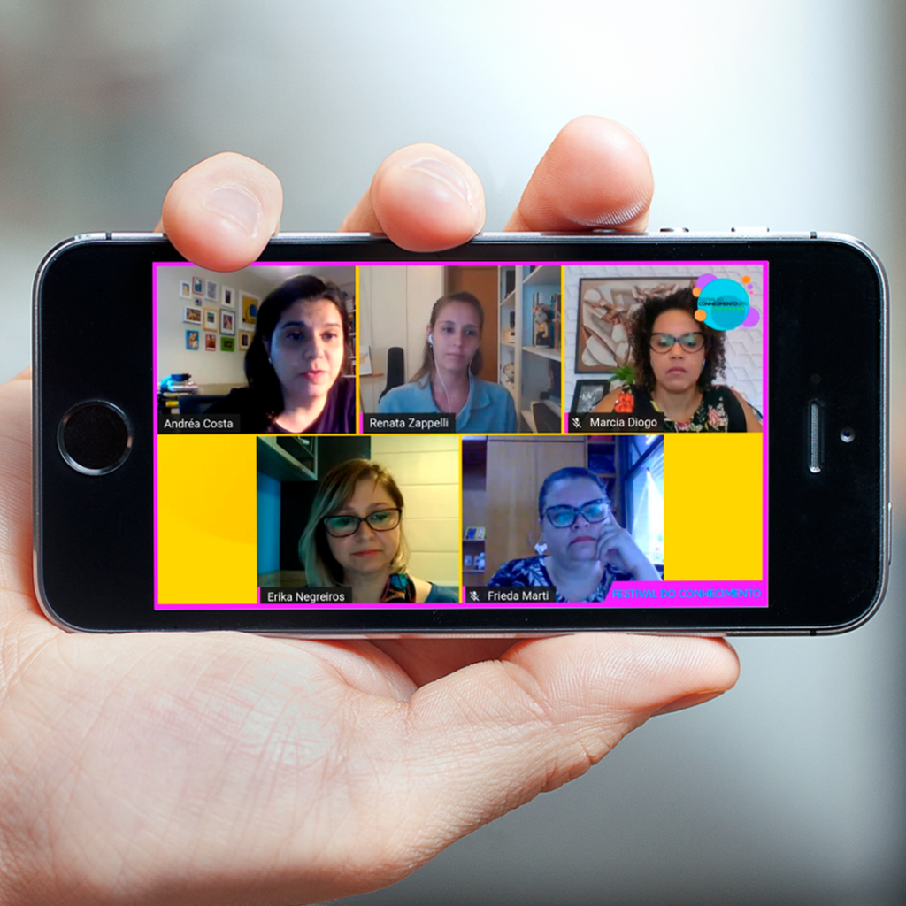 Fotografia de uma mão segurando um celular com o vídeo da live “Museus Universitários e Redes Sociais Digitais: desafios e potencialidades”, do painel temático do Festival do Conhecimento da UFRJ.