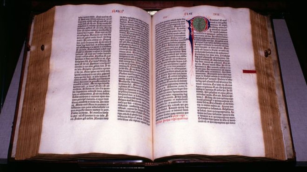 Fotografia da Bíblia de Gutenberg aberta em cima de uma mesa.